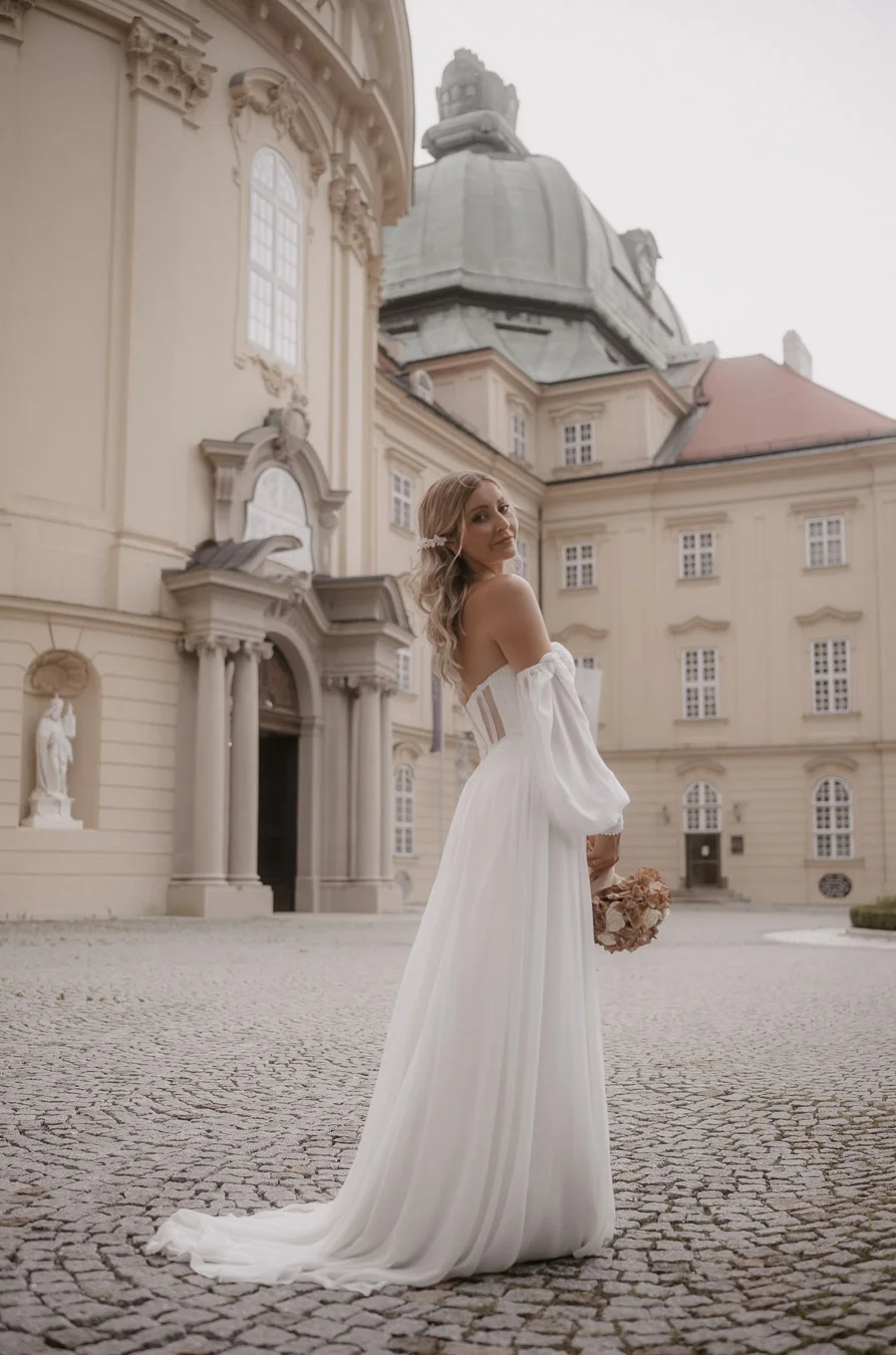 Braut in einem wunderschönen Brautkleid hält einen Brautstrauß in ihren Händen